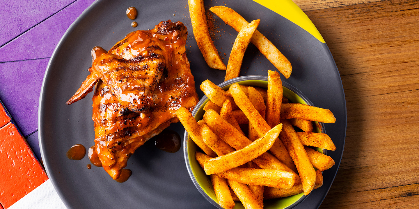 a Nando’s meal on a table including PERi-PERi chicken, a salad, chips, and a selection of sides